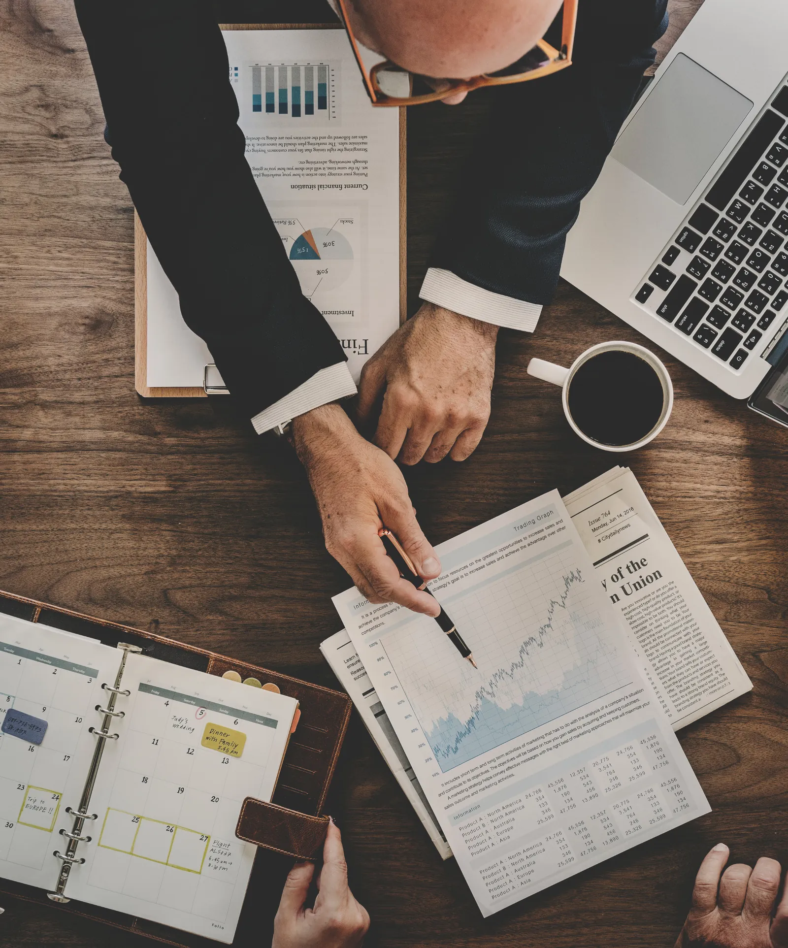 Hands pointing at market research and charts spread across a desk