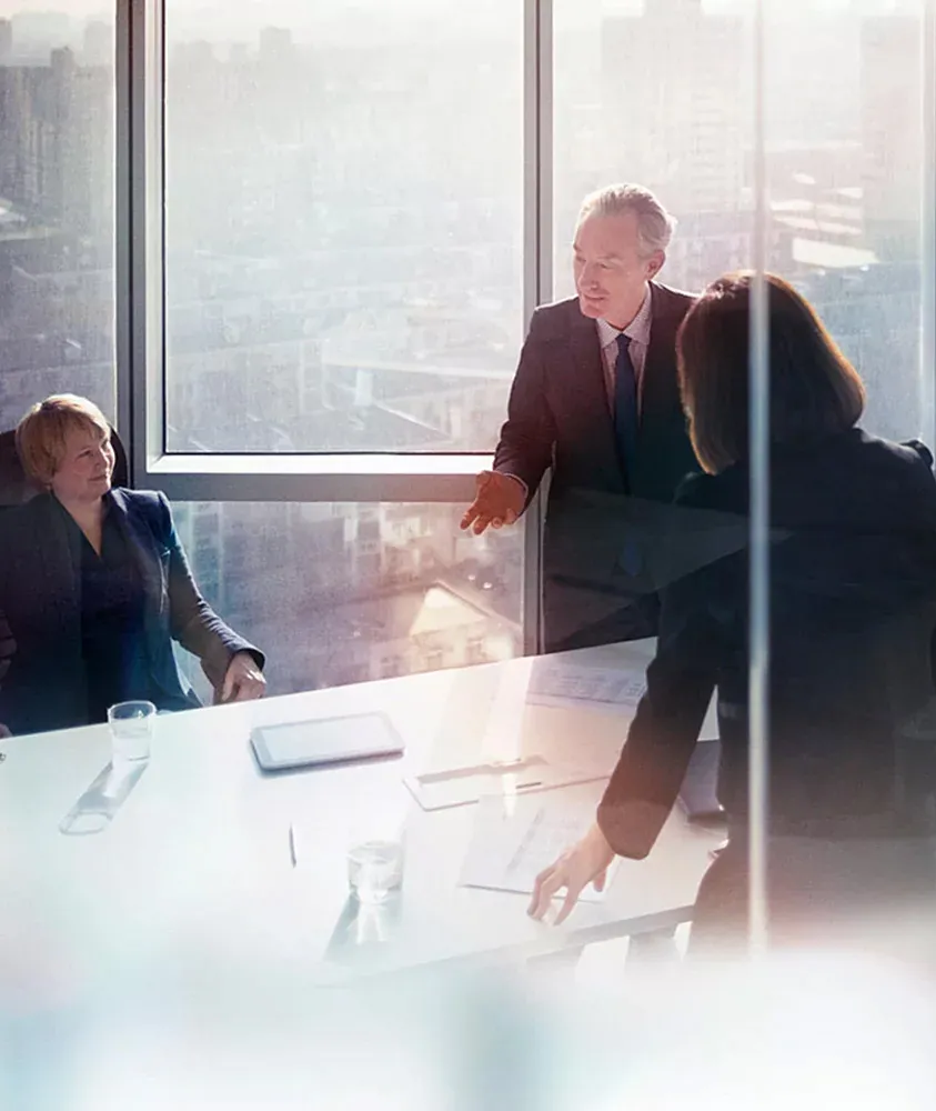 A team in discussion at a boardroom table by a window